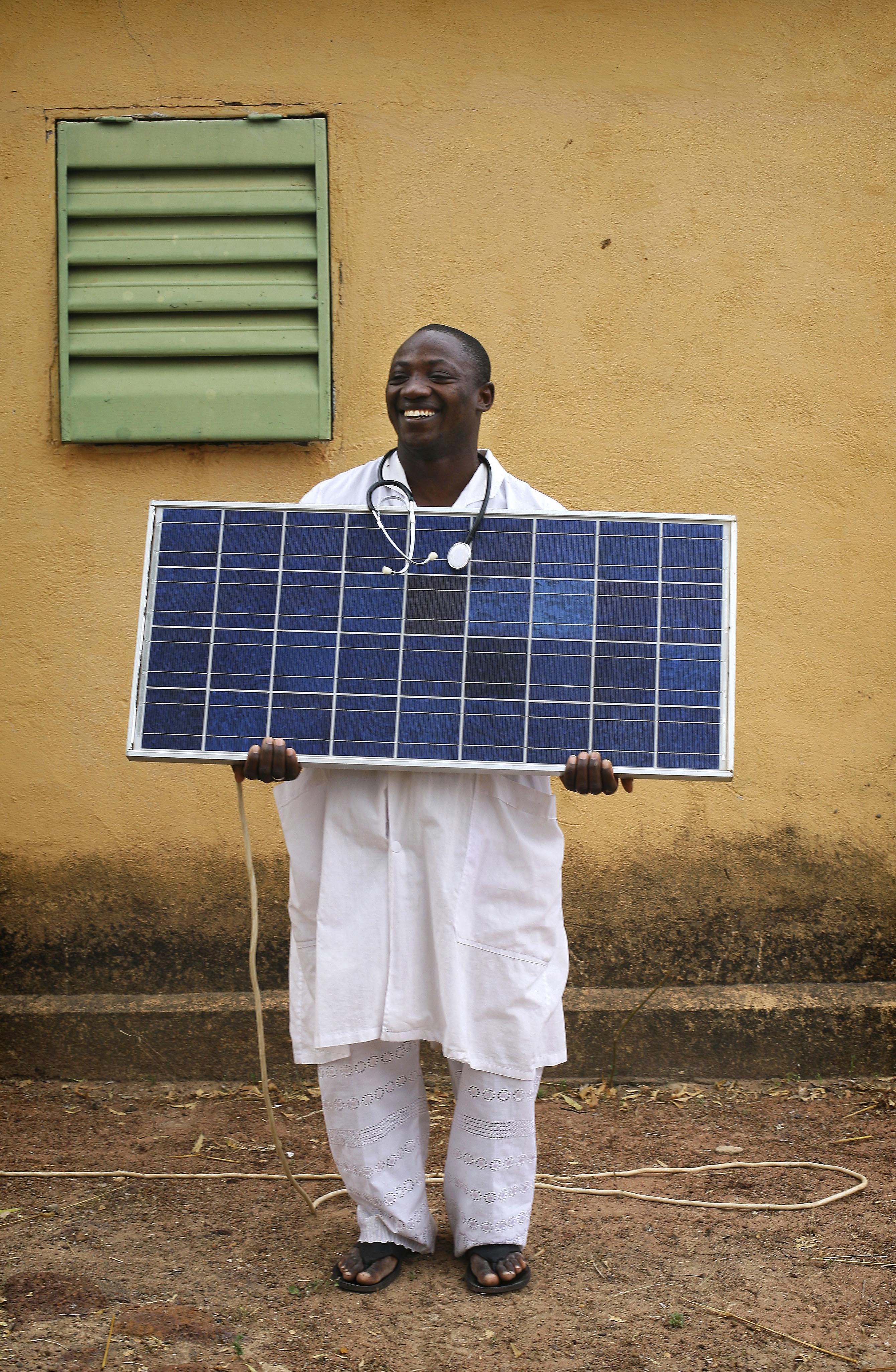 A doctor in Mali holding a solar panel